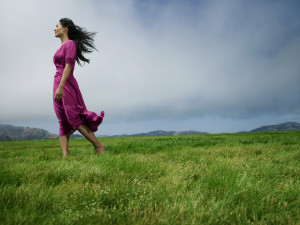 Woman standing in field barefoot